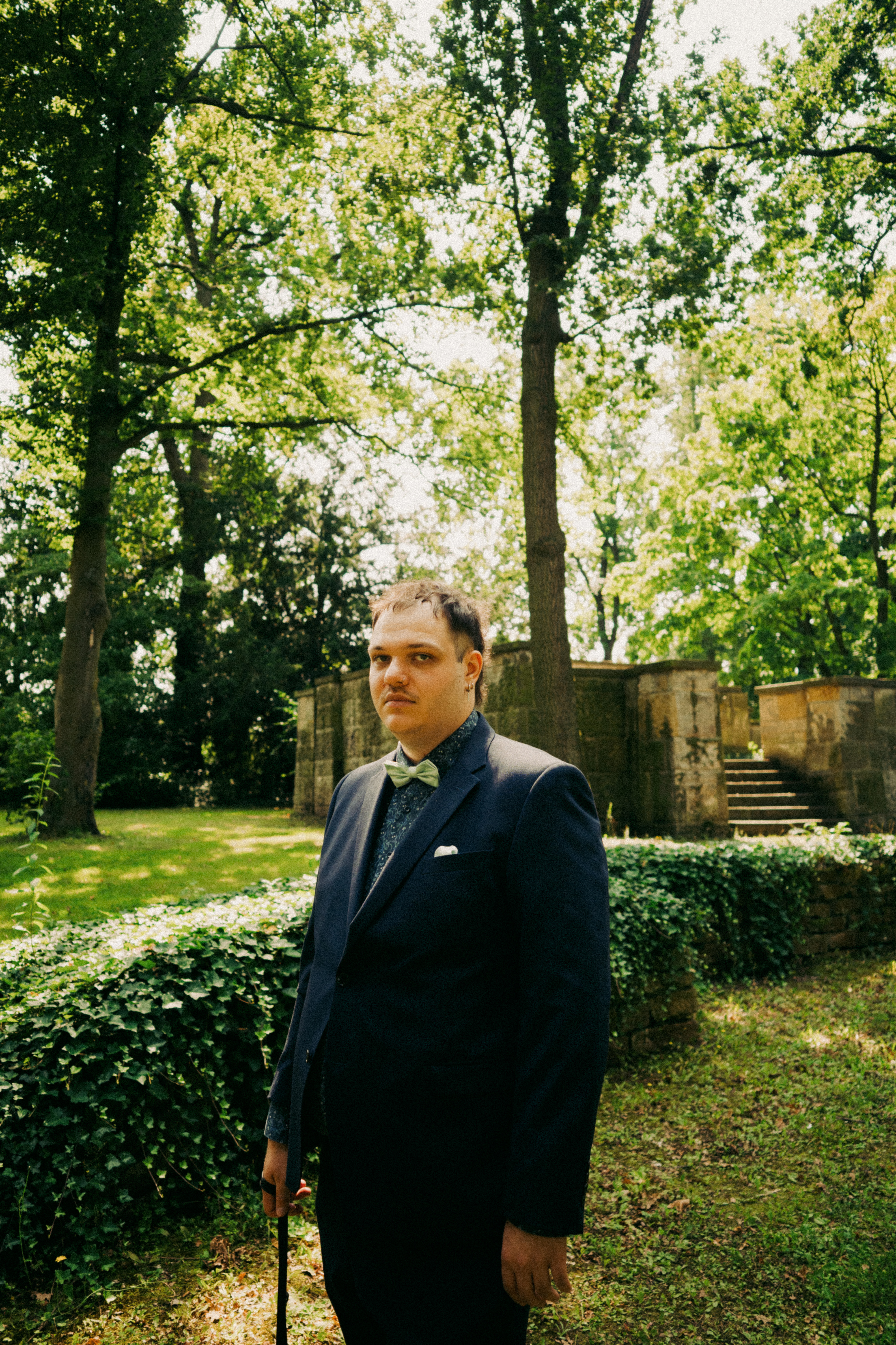 Potrait von Lovis Wild im Anzug mit Fliege, Farbe, im Park